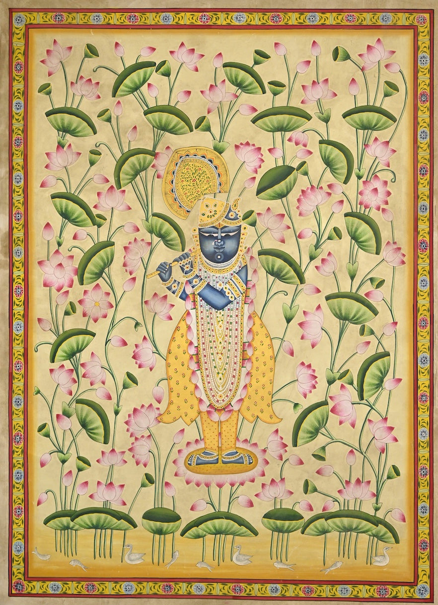 Krishna playing the flute among pink lotuses and green leaves on a pale golden background, framed by a painted floral border.