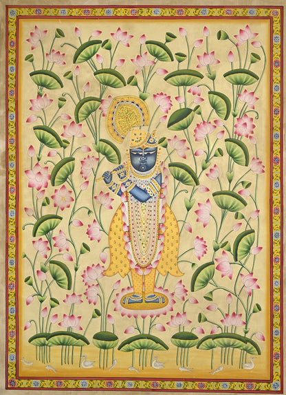 Krishna playing the flute among pink lotuses and green leaves on a pale golden background, framed by a painted floral border.