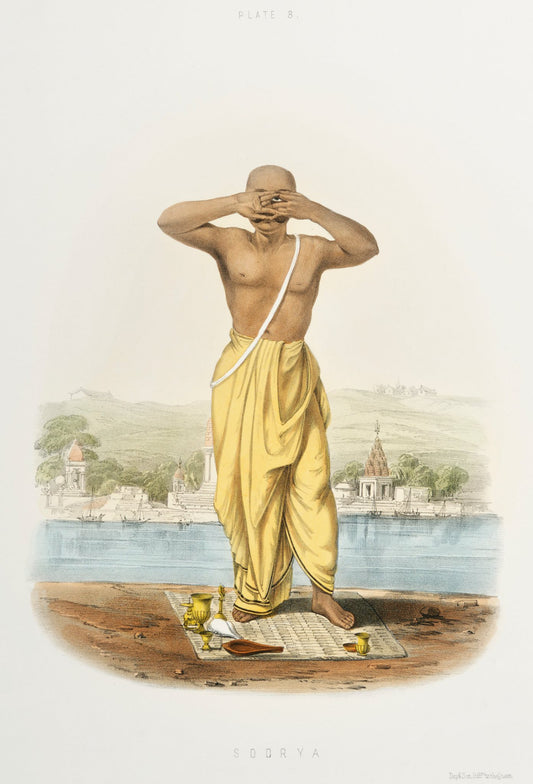 A devotee in a bright yellow garment stands beside water, his raised hands forming the focus of this quiet ritual study.